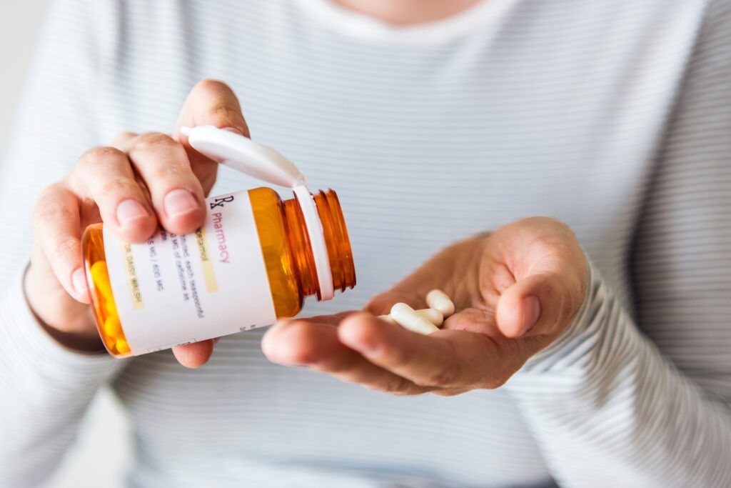 Person pouring pills from a prescription bottle | medical malpractice attorneys​ | Menzer Law|A medical professional writes on a prescription bottle | medical malpractice law firm​ | Menzer Law|A physician hands a prescription to a patient | medical malpractice attorneys​ | Menzer Law