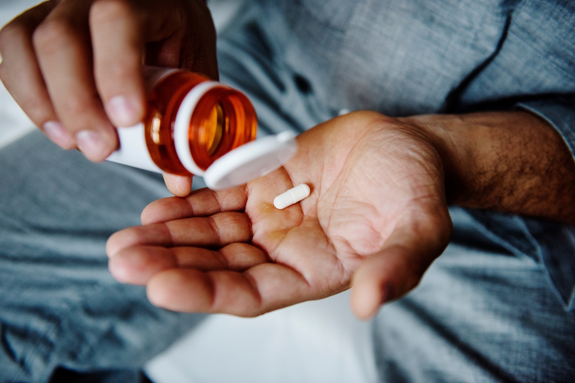 Person pouring a single capsule from an orange bottle | medical malpractice lawyer​ | Menzer Law|Doctor hands patient a pill bottle in clinic setting |medical malpractice law firm​ | Menzer Law|A handshake between two individuals at a desk | personal injury law firm​ | Menzer Law