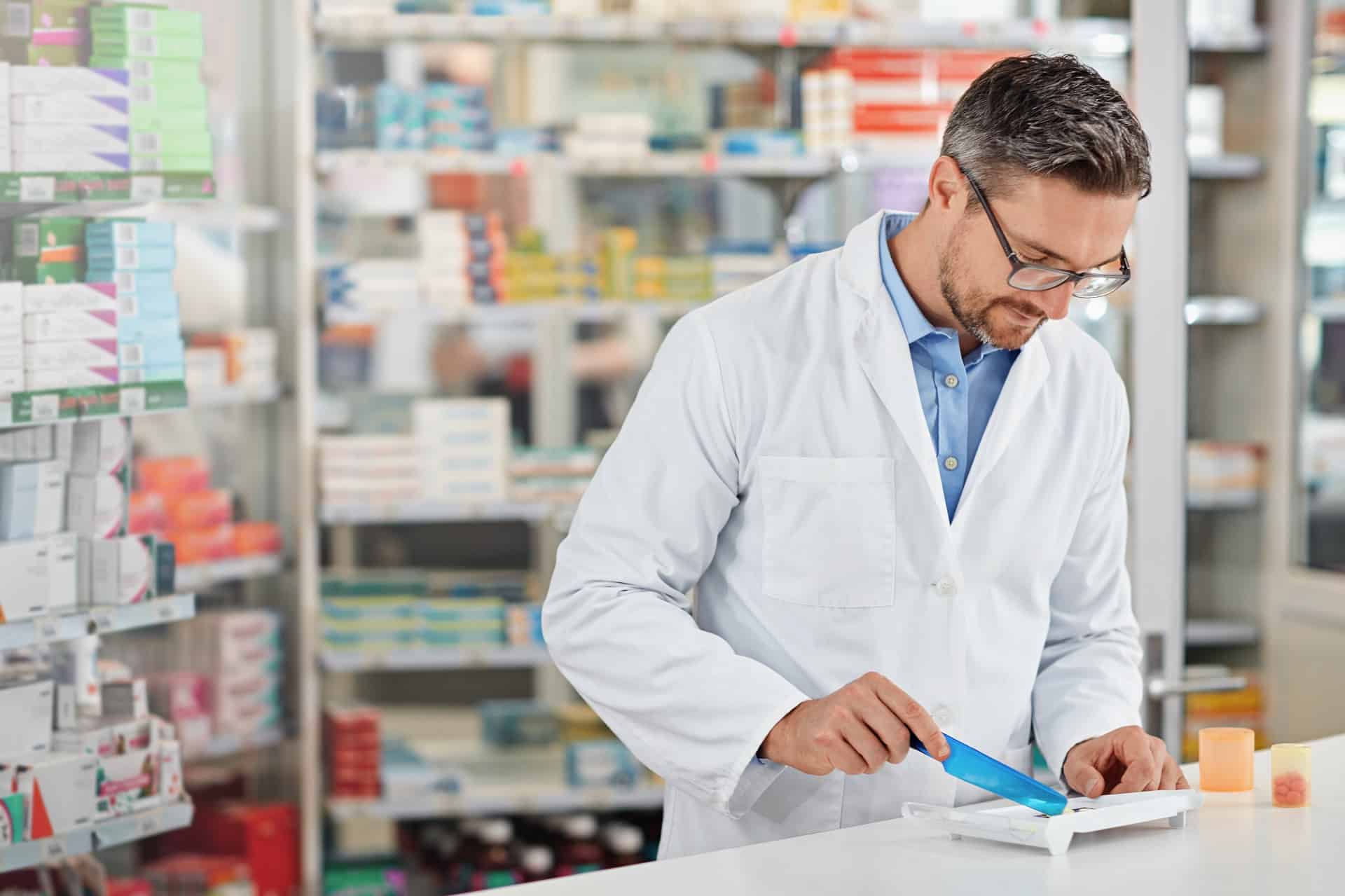 Pharmacist in a white coat writing in a pharmacy | medical malpractice attorneys​ | Menzer Law|A man holds a handful of pills | medical malpractice law firm​ | Menzer Law|Lawyer completes paperwork