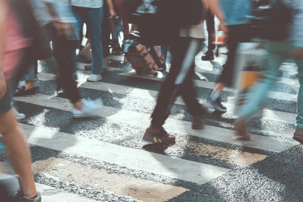A busy crosswalk with several people walking across it.
