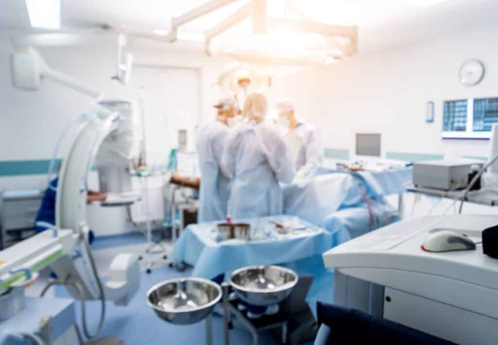 A group of surgeons standing together next to a hospital bed.