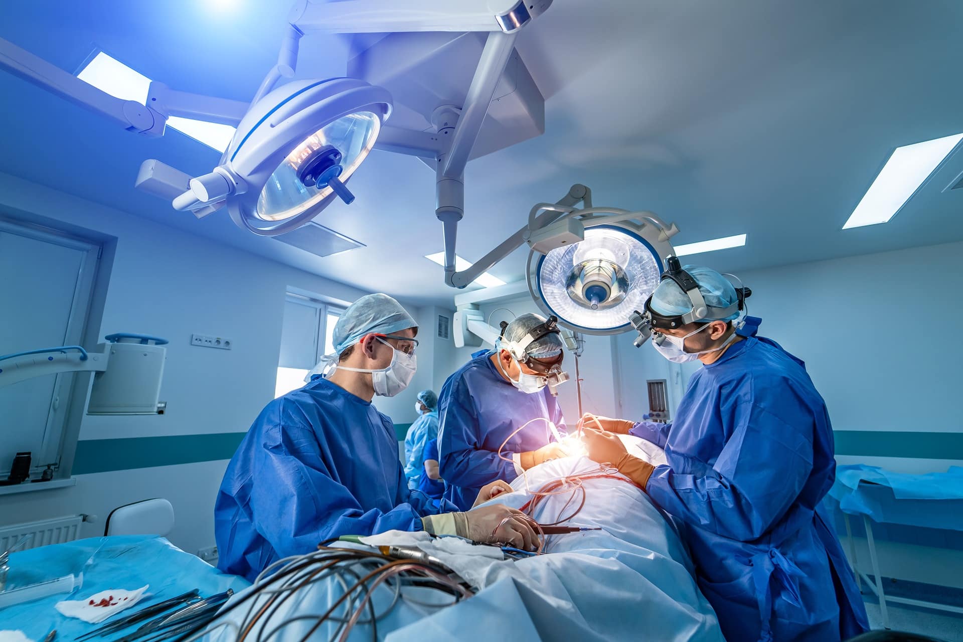 A team of surgeons operating on a patient in a hospital room.