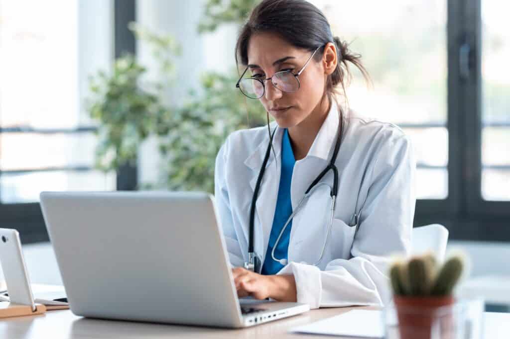 A female doctor sitting behind a laptop in an office.