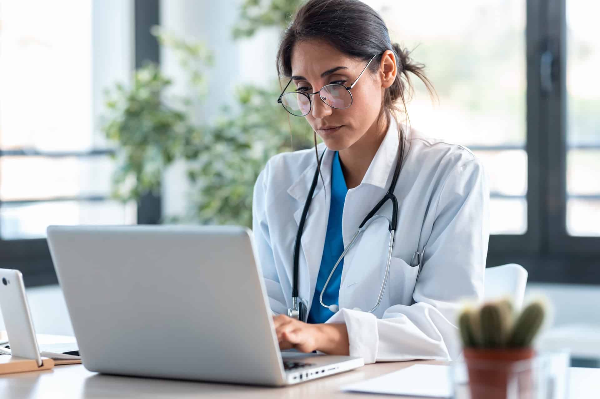 A female doctor sitting behind a laptop in an office.