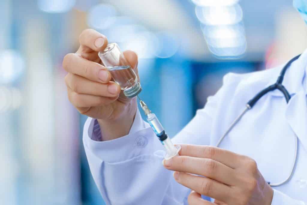 A doctor fills a syringe with medicine in a hospital.