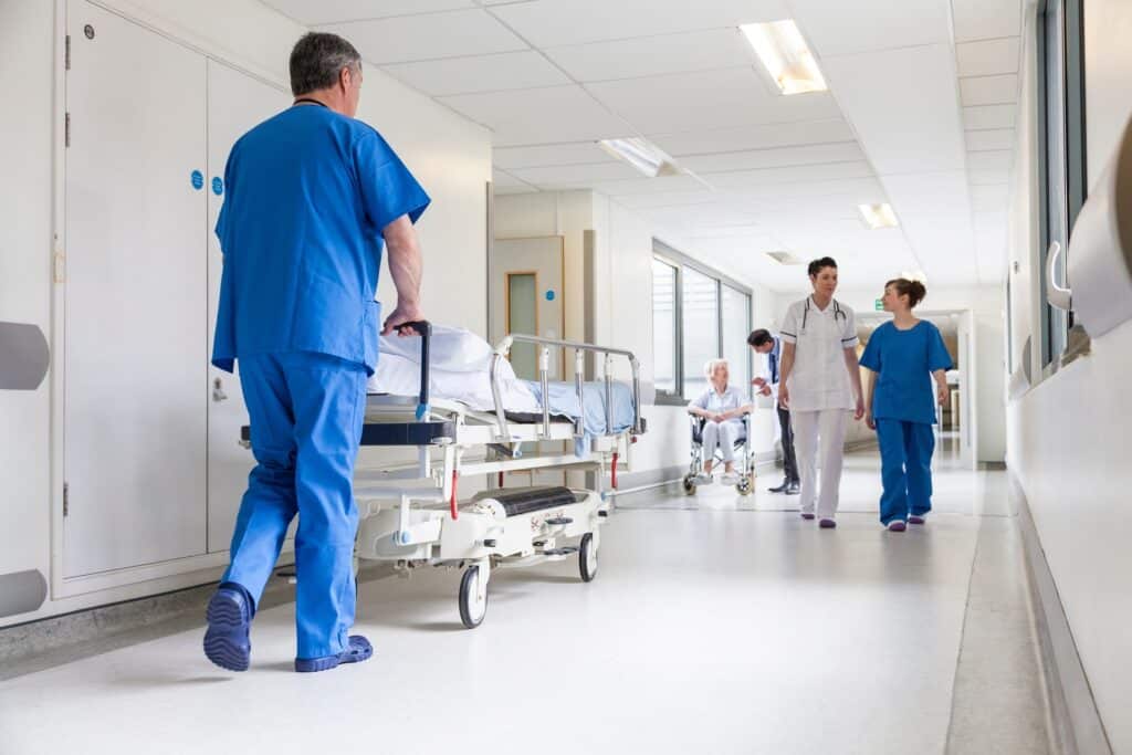 A busy hospital hallway with nurses and doctors walking.