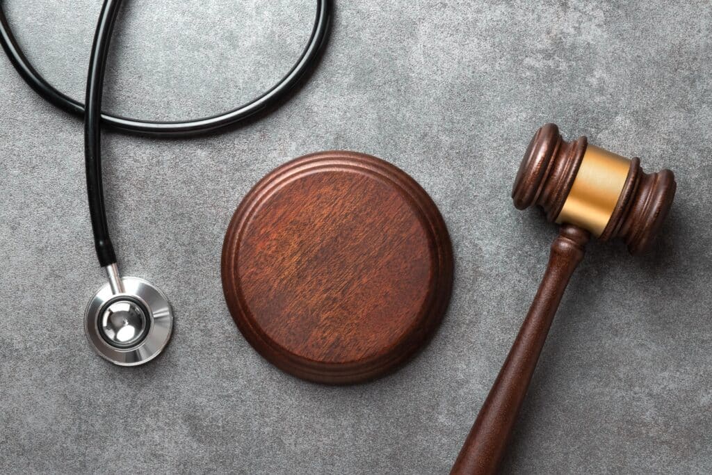 A gavel rests next to its stand and a curled up black stethoscope.