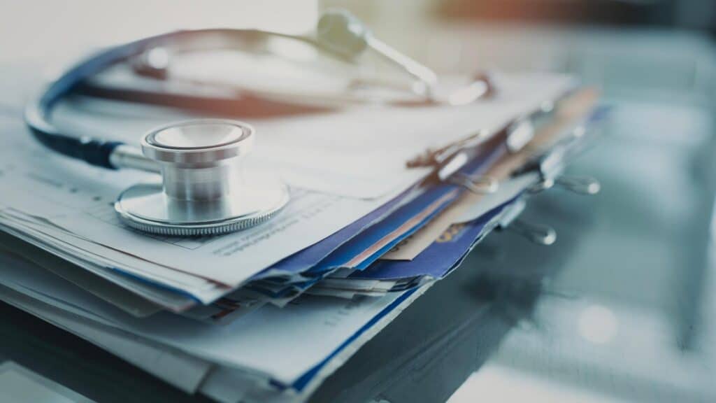A stethoscope rests on a stack of medical documents.